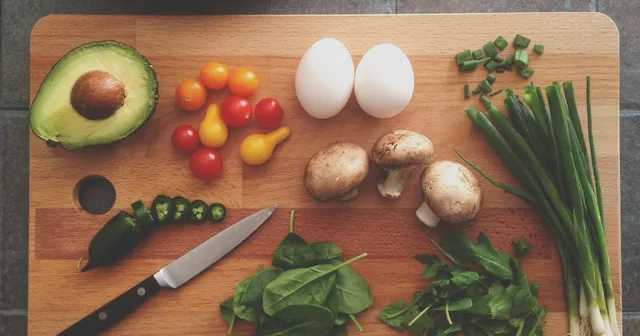 Vegetables on a wooden board with a knife with a pan on top